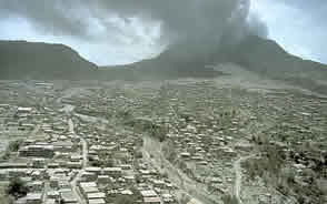 The Soufriere Hills volcano smokes over the destroyed town of Plmouth. MVO
